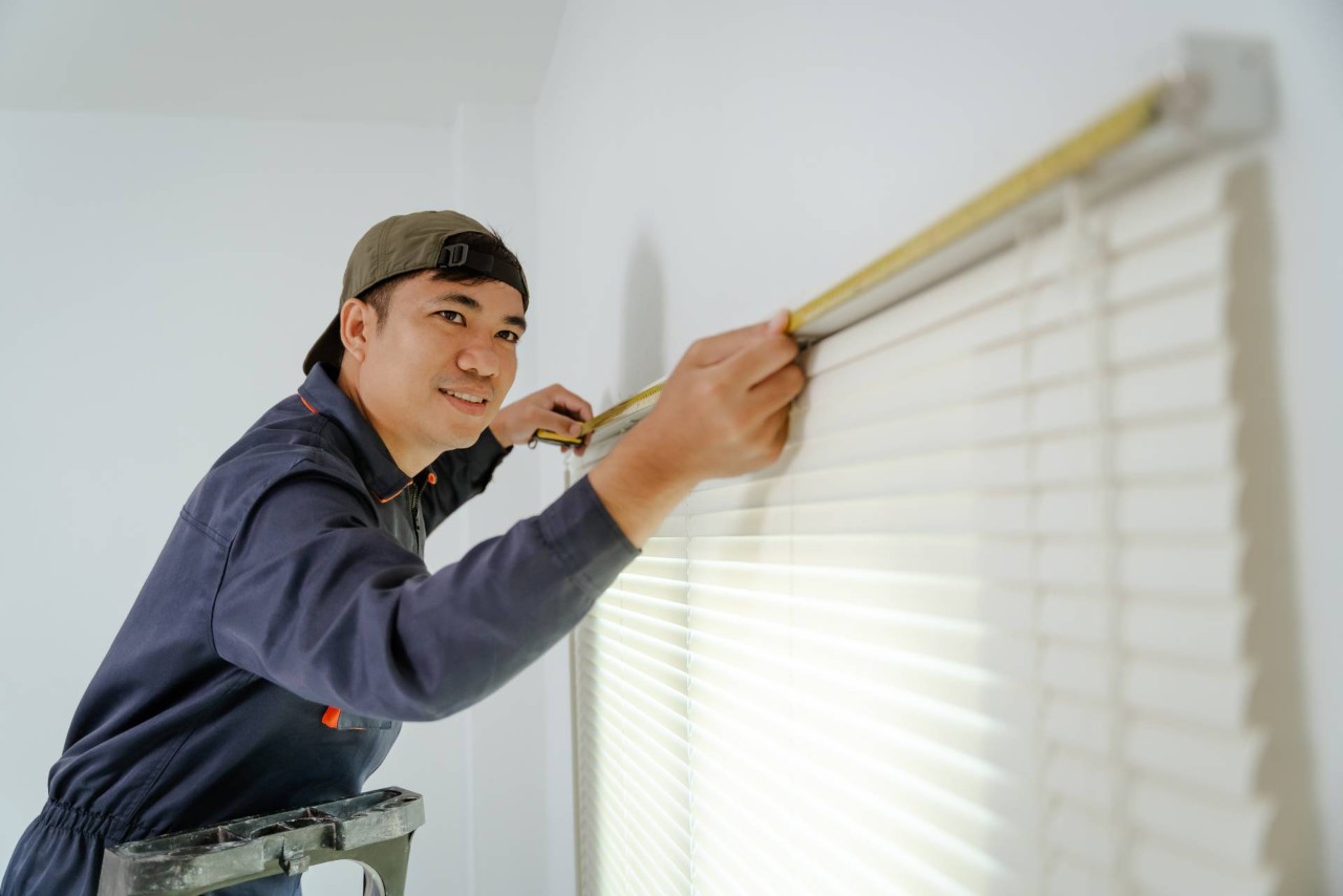 A professional measuring a window for custom window blinds at Window Trends near Kalaheo, Hawaii
