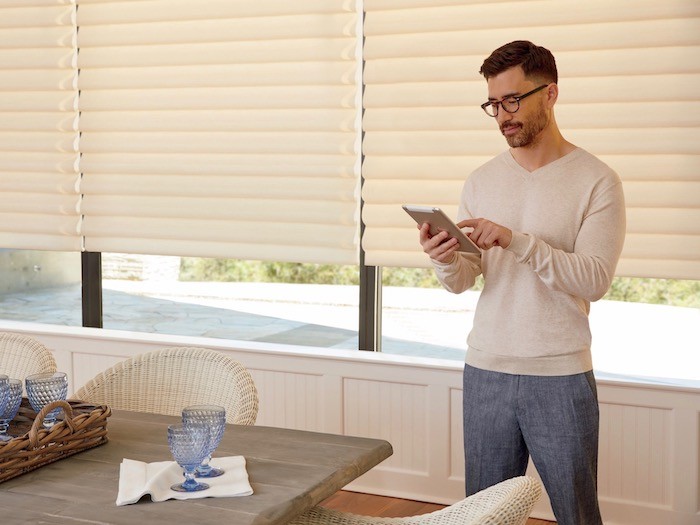 Man standing next to dining table holding a tablet.